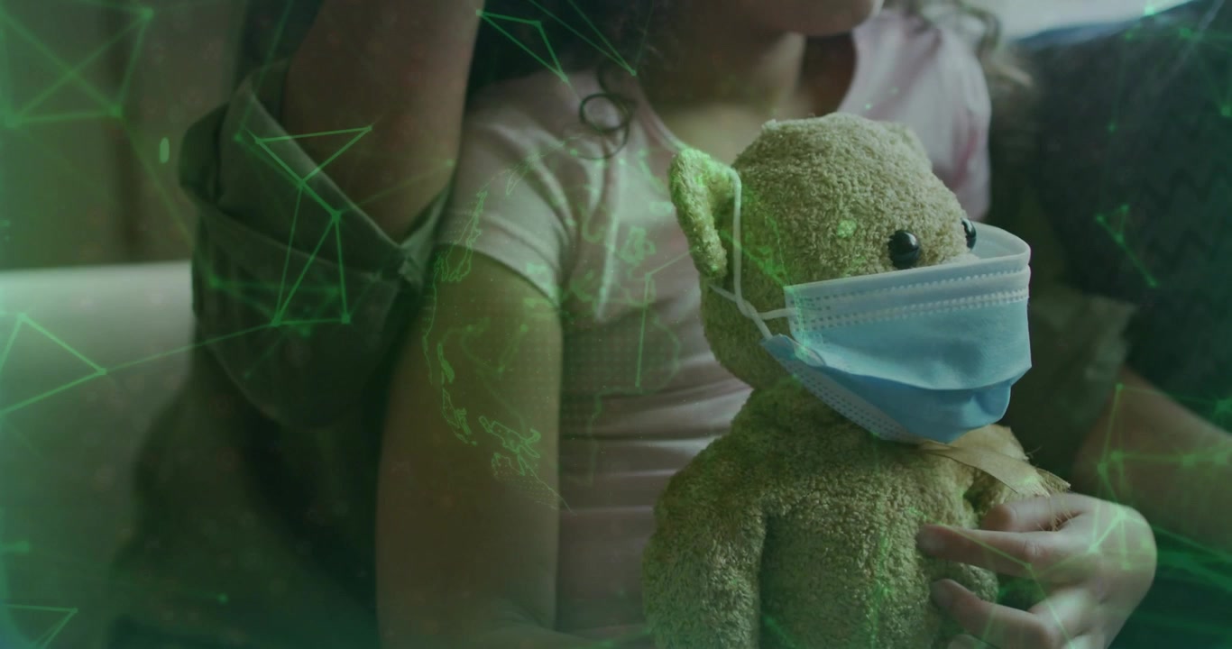Child holding masked plush while adult supporting camera zooming and green overlay framing health