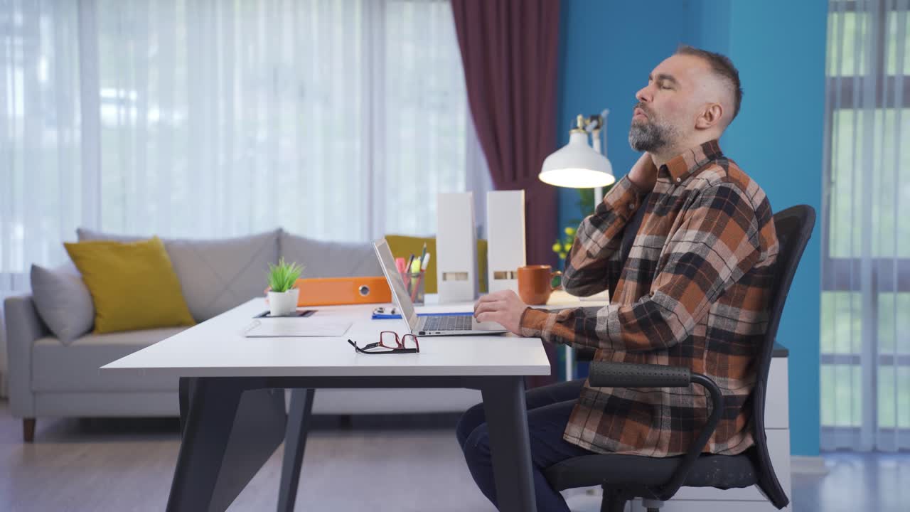 el hombre adulto que trabaja desde casa está muy cansado, le duele el cuello y la espalda.