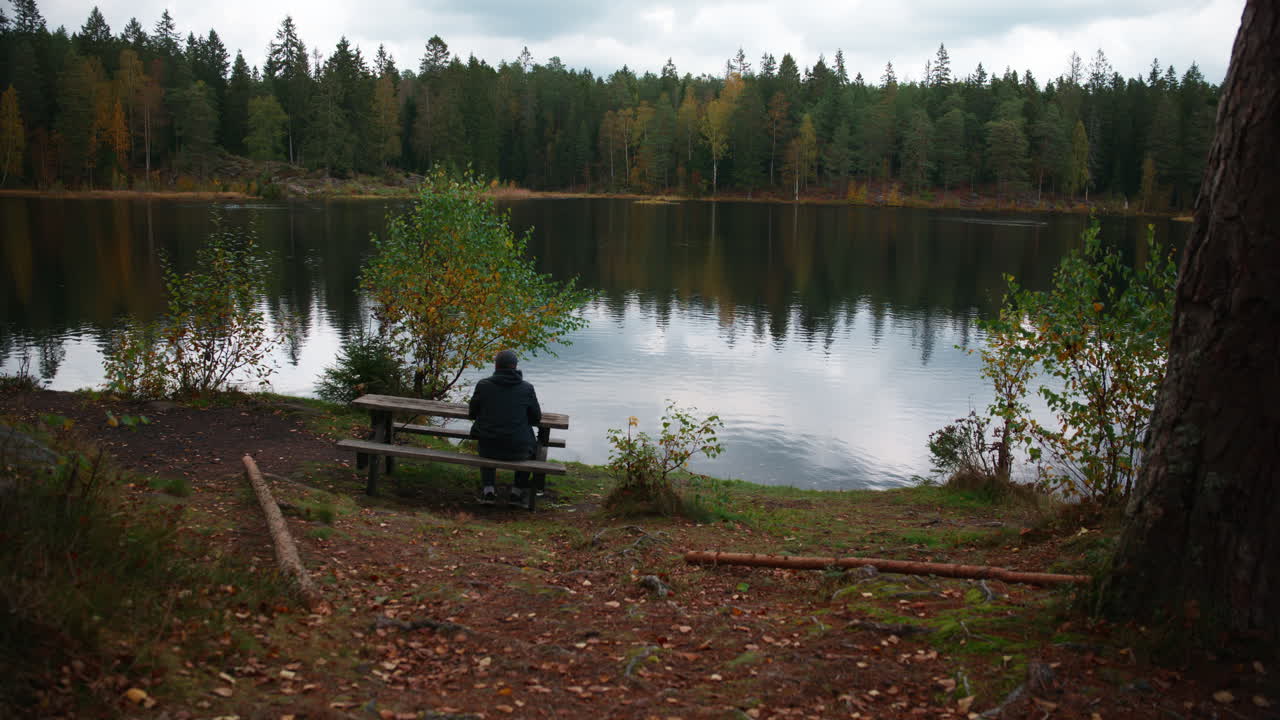 A man sits alone and enjoying the scenic view and the lake