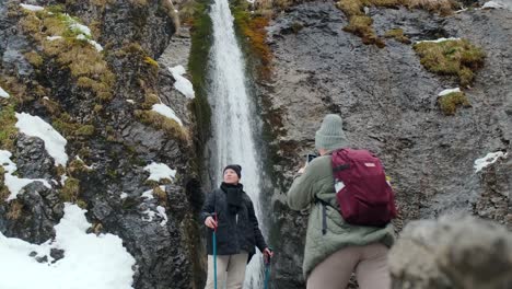 hikers taking pictures of a waterfall in the winter mountains