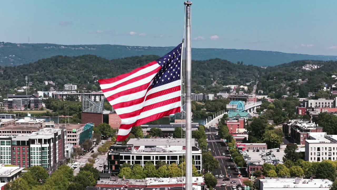 Primo piano aereo di una bandiera americana che sventola sul centro di Chattanooga, con il Tennessee Aquarium visibile sullo sfondo