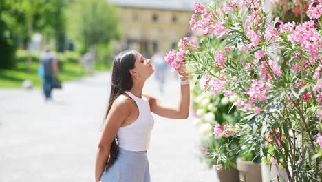 woman smelling pink flowers in a city garden