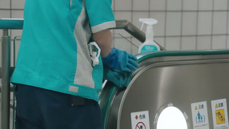 cleaner's hands with rubber gloves sanitizing handrail of escalator in japan - covid-19 prevention - close up, slow motion