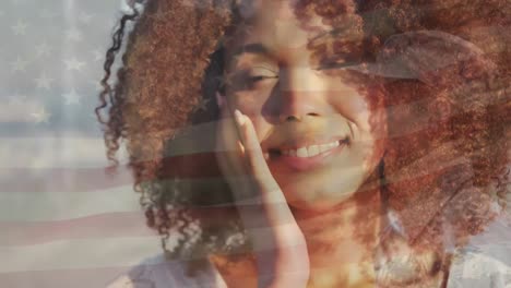 animation of flag of united states of america over african american woman on beach