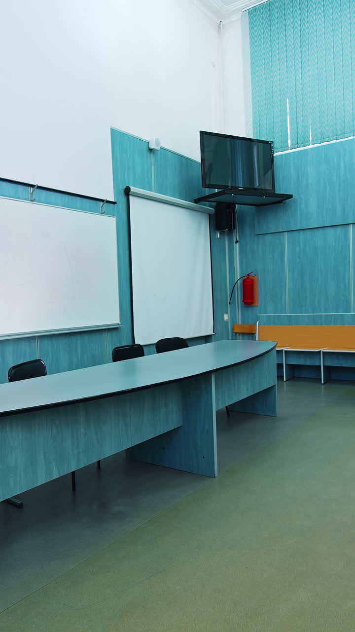 Modern interior of lecture hall. White board and presidium table in the university classroom. Empty auditorium with new equipment. Vertical video