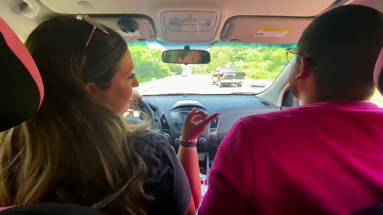 Donna bianca e uomo gay di etnia mista che cantano in macchina durante un lungo viaggio in auto