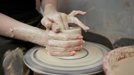 a potter teaches a woman to make clay dishes. a man takes a woman's hands