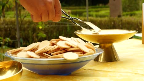 a host is placed from one bowl into another with tongs