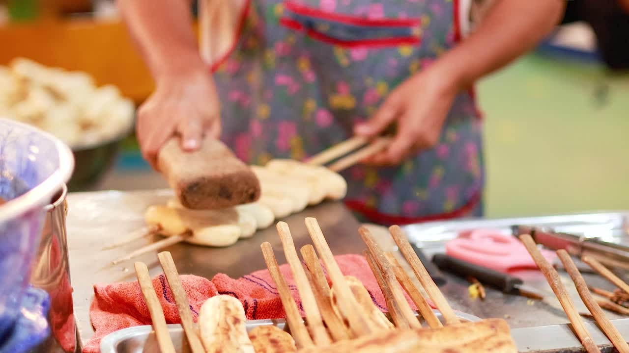 vendedor prepara plátanos a la parrilla en el mercado de bangkok