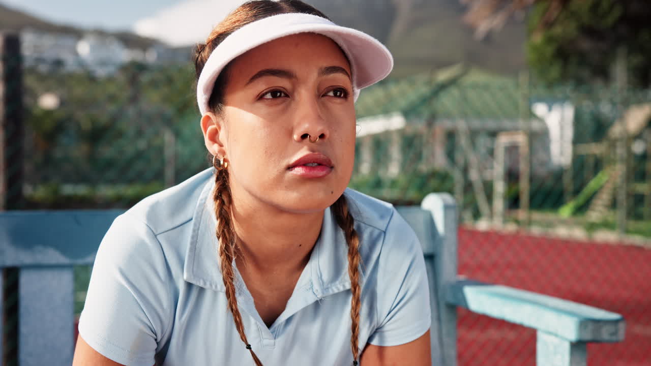 A tennis player sits on a bench