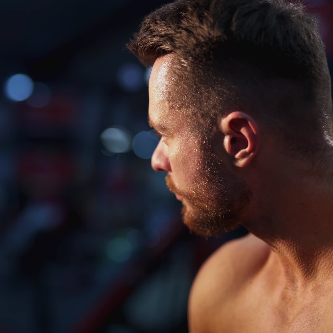 Tired bodybuilder resting after training. Young handsome athlete sitting and drinking water. Close-up portrait of a sportsman