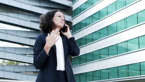 Cheerful-businesswoman-talking-by-smartphone