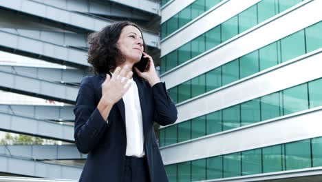 cheerful businesswoman talking by smartphone