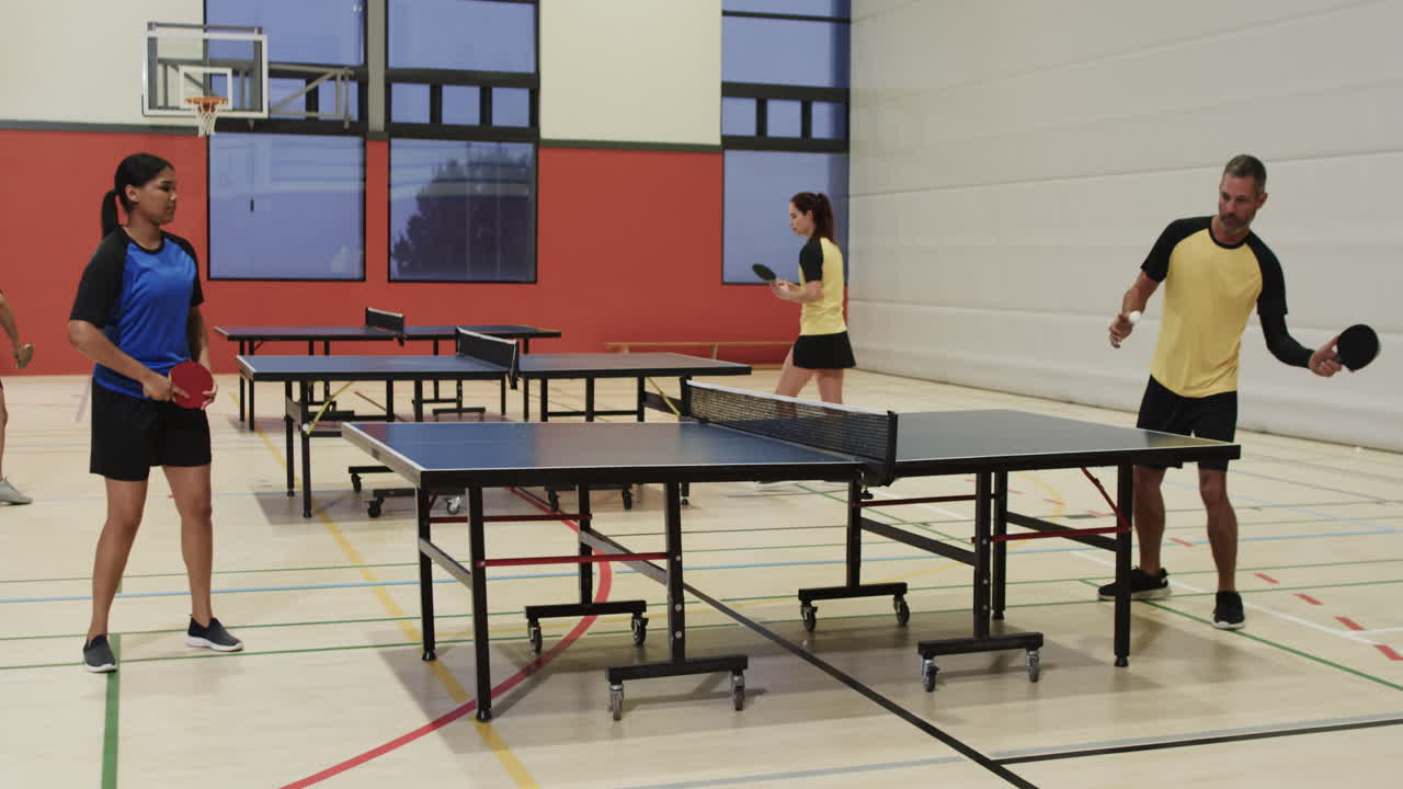 Playing table tennis, people practicing in indoor sports facility with paddles