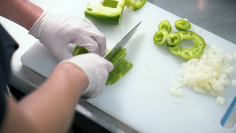 Der-Koch-Schneidet-Grünen-Paprika-Auf-Dem-Schneidebrett-In-Dünne-Scheiben,-Zeitlupe-Von-Oben-Nach-Unten,-4k