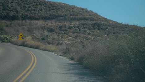 Slow-Motion-drive-on-winding-road-near-coast-on-bright-sunny-day