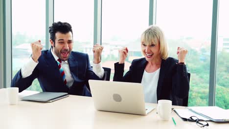 two happy business people celebrate at office