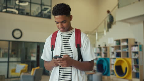 teenage student using mobile phone in library