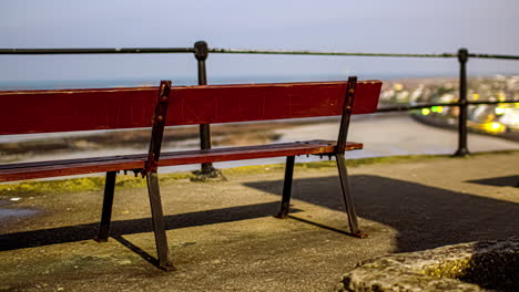 hyperlapse behind a bench overlooking a seaside town illuminated by lights