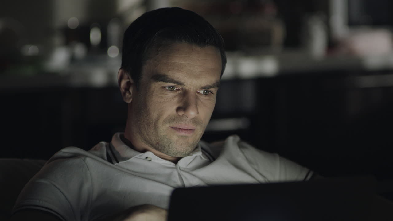 hombre cansado trabajando hasta tarde con una computadora portátil por la noche en casa.