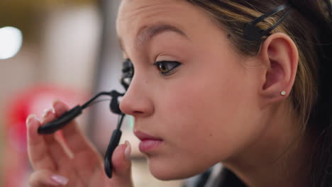 close-up of young lady gently applying makeup using an eyelid opener, carefully enhancing her eyes, focus on beauty routine, skincare, and attention to detail in makeup application