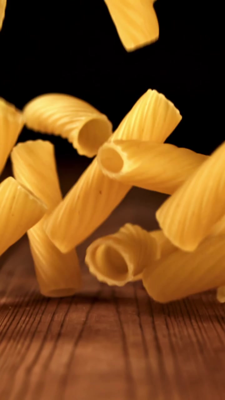 Ripresa al rallentatore di pasta secca che cade su uno sfondo di legno