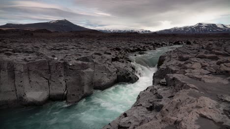 fast river flowing between basalt landscape during cloudy day