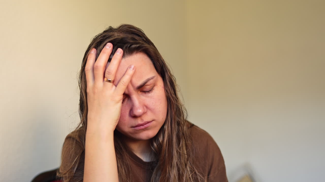 Donna senza trucco in stato depressivo. Donna triste con le lacrime agli occhi. Donna trascurata con mal di testa. Emicrania nelle donne