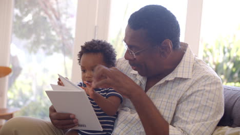 grandfather and grandson reading book at home together