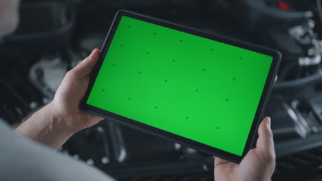 mechanic using tablet with green screen for car diagnostics