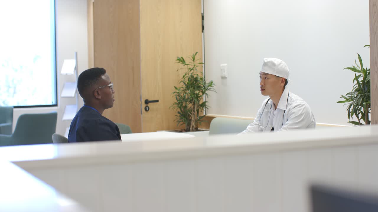Diversos médicos do sexo masculino, médico cobrindo o rosto, colega gesticulando, falando sobre cuidados em clínica com divisória baixa