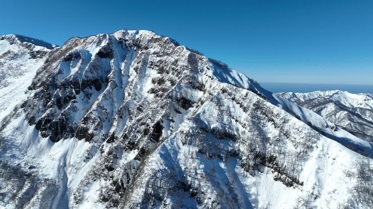 Inquadratura di apertura orbitante del monte Myōkō in Giappone, volando intorno alla montagna in una limpida giornata invernale, una montagna vulcanica nella regione del Parco Nazionale Myoko-Togakushi Renzan