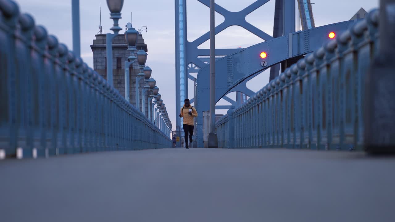 Male Jogger Running Along Walkway Of Benjamin Franklin Bridge Connecting Philadelphia, Pennsylvania, and Camden, New Jersey. - wide static
