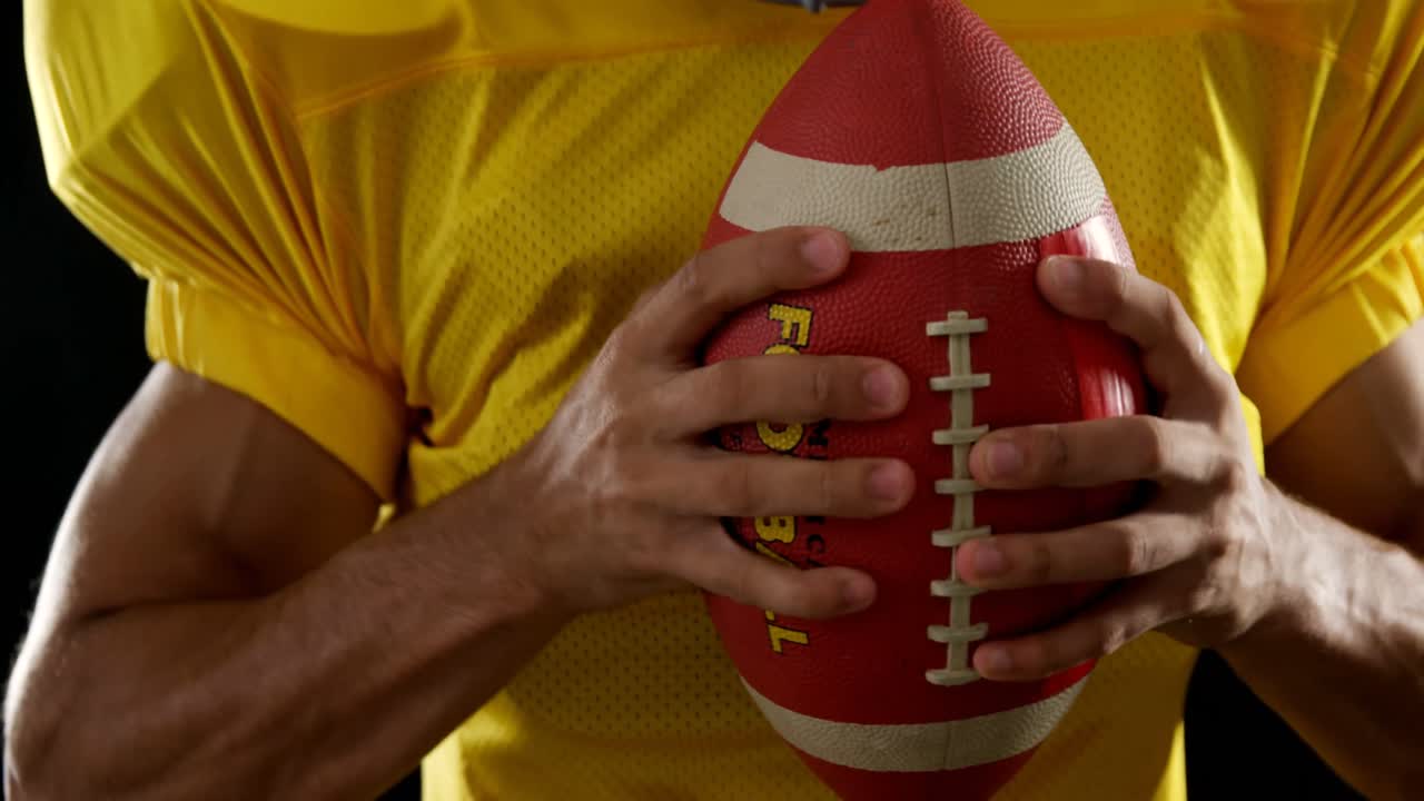 Giocatore di football americano con il pallone in mano su sfondo nero 4k
