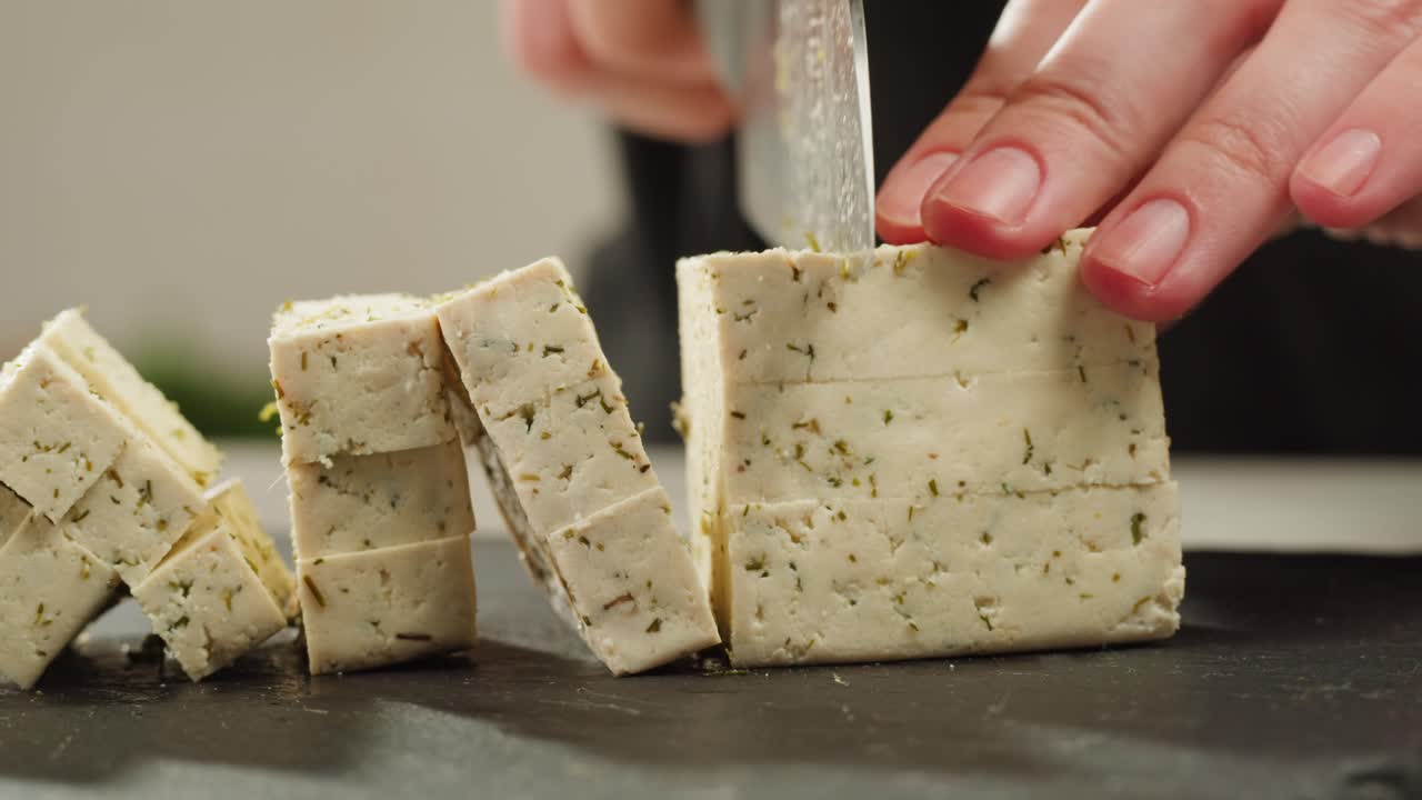 Fried tofu with sesame seeds and spices on cast iron pan, cooking japanese salad. Healthy ingredient for cooking vegan vegetarian diet food. Roasted tofu over black background.