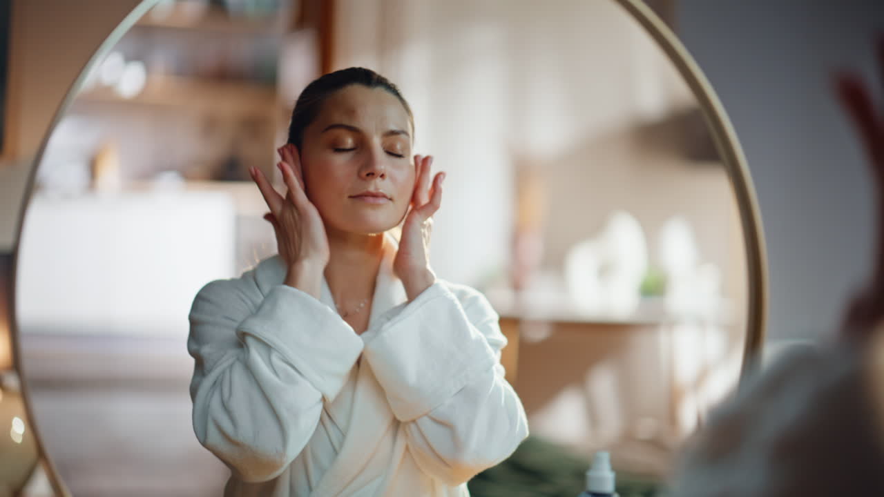 Woman making facial massage at mirror home bedroom closeup. Lady massaging