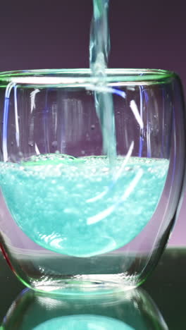 pouring a vibrant blue drink into a glass