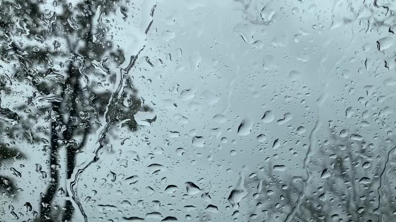 gotas de lluvia cayendo sobre una ventana de vidrio transparente formando rayas como lágrimas en un día sombrío