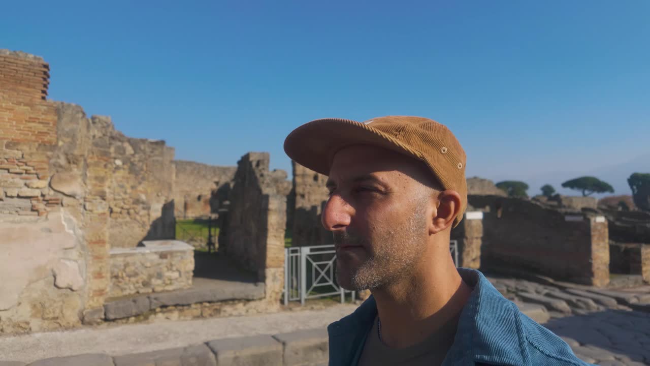 Un turista di circa 40 anni esplora la via principale di Pompei nel parco archeologico, ammirando l'antico layout urbano romano e l'atmosfera storica
