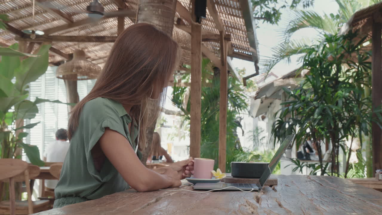 Long-haired Woman Video Calling in Tropical Cafe