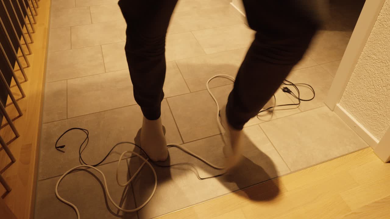 A person accidentally trips over tangled cables on the floor. Everyday household hazard showing carelessness and risk