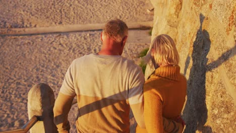 senior couple walking alongside beach