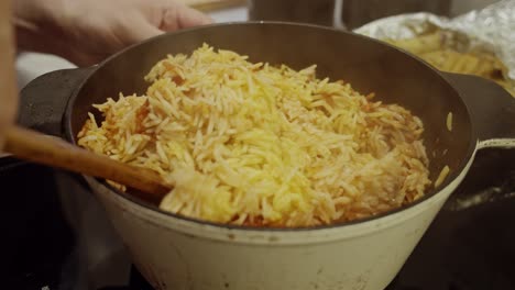stirring freshly baked biriyani rice with wooden spoon