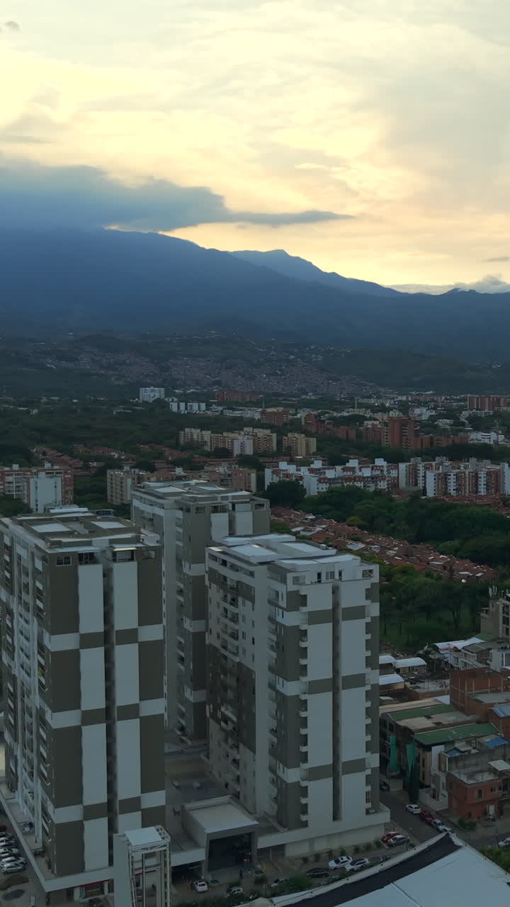 Captivating aerial vertical video of Valle del Lili, Cali, showcasing urban architecture against a stunning sunset sky. Ideal for mobile, social media, and vertical content platforms