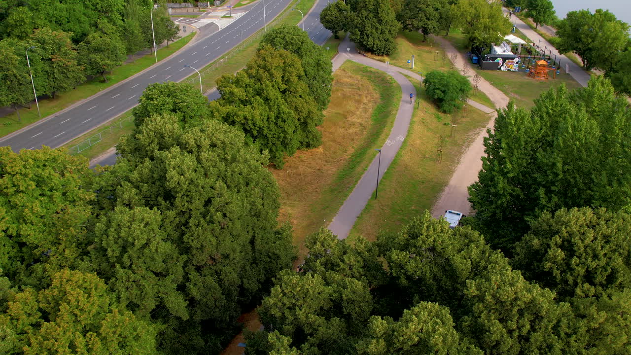 Aerial top down shot of cyclist on path between forest during sunny day in Poland