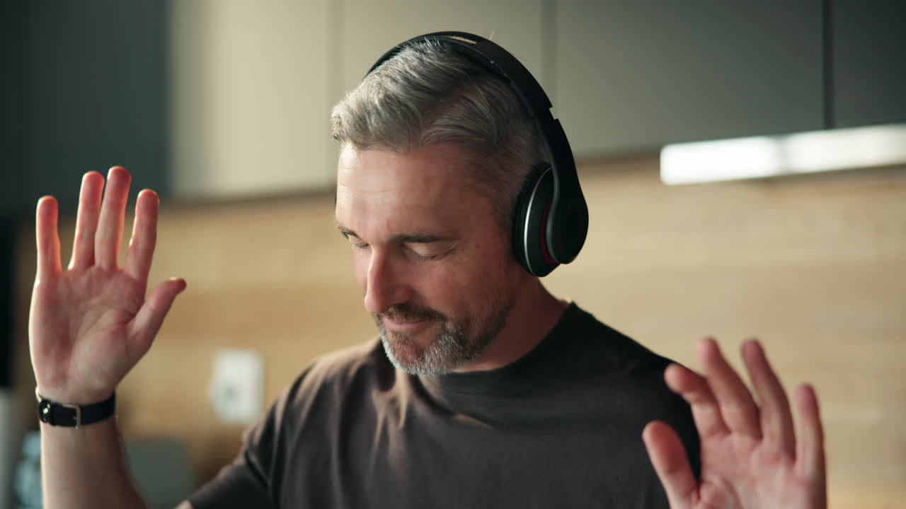 Glad mann med hodetelefoner som danser til musikk hjemme