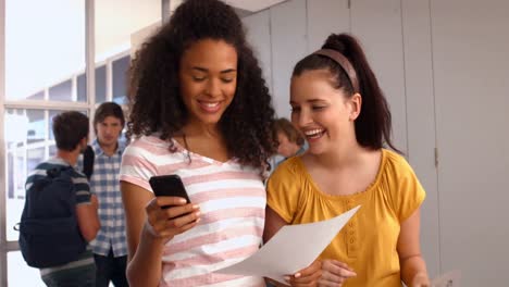 estudiantes felices mirando teléfonos inteligentes en la universidad
