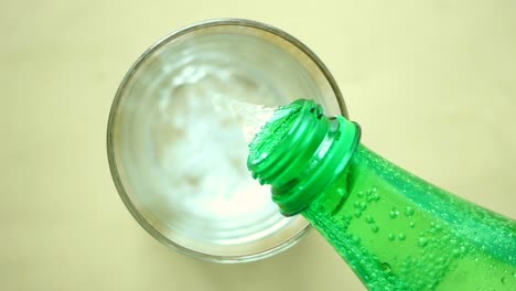 vertiendo agua gaseosa de una botella verde en un vaso