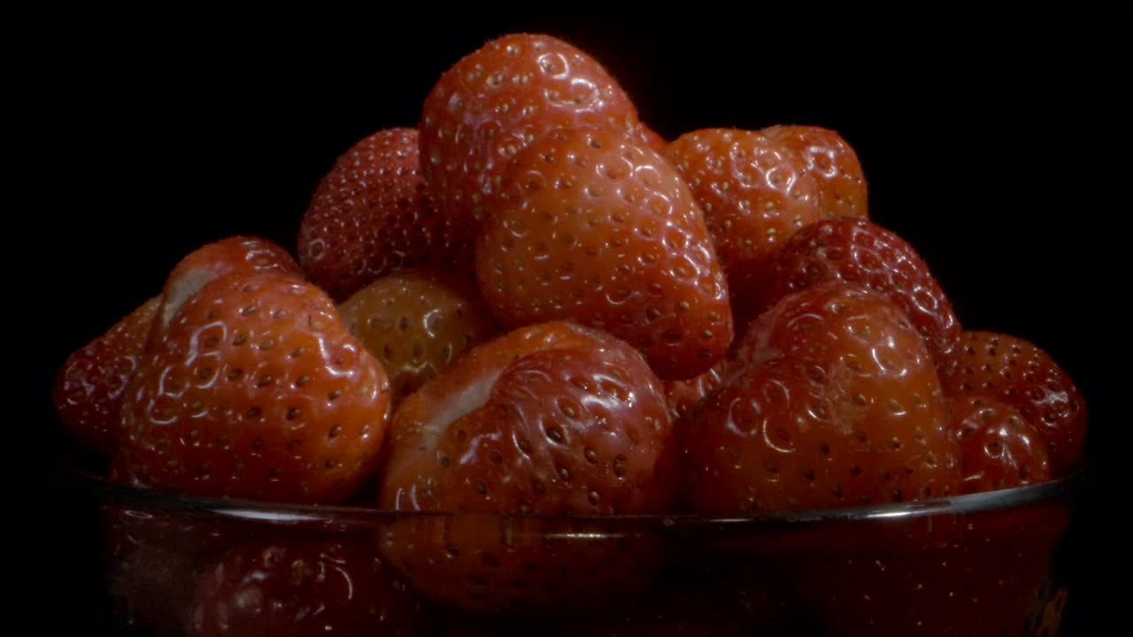 흑색 바탕에 은 스크린에서 빨간 딸기를 회전합니다. 카메라 회전 360도, 클로즈업.