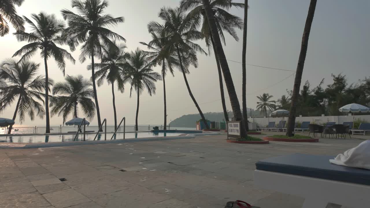 4K video of a swimming pool area with sun lounges and a pool with palm trees